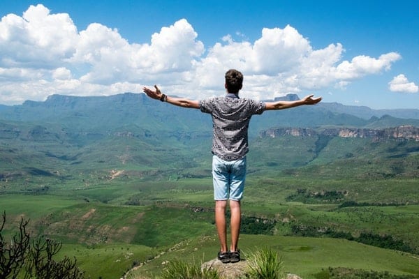Photo of a man standing high on a mountain celebrating personal goals for 2019