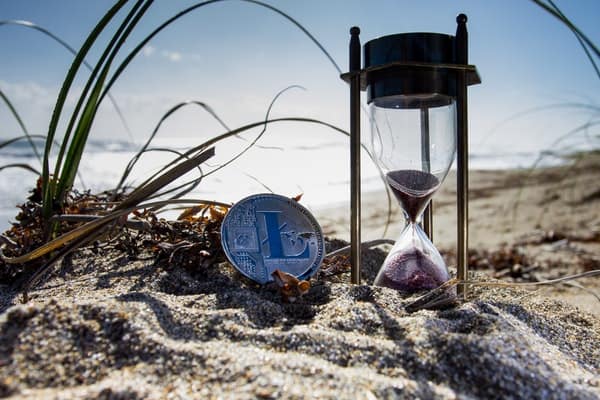A coin and sand timer on a beach signifying to just start investing as a young debt-free family