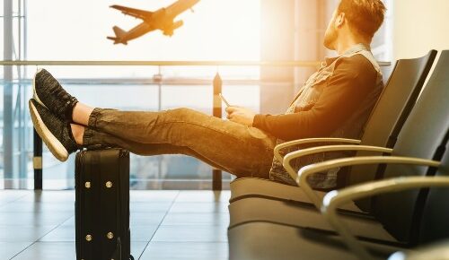 travel jobs photo of man in airport watching plane takeoff