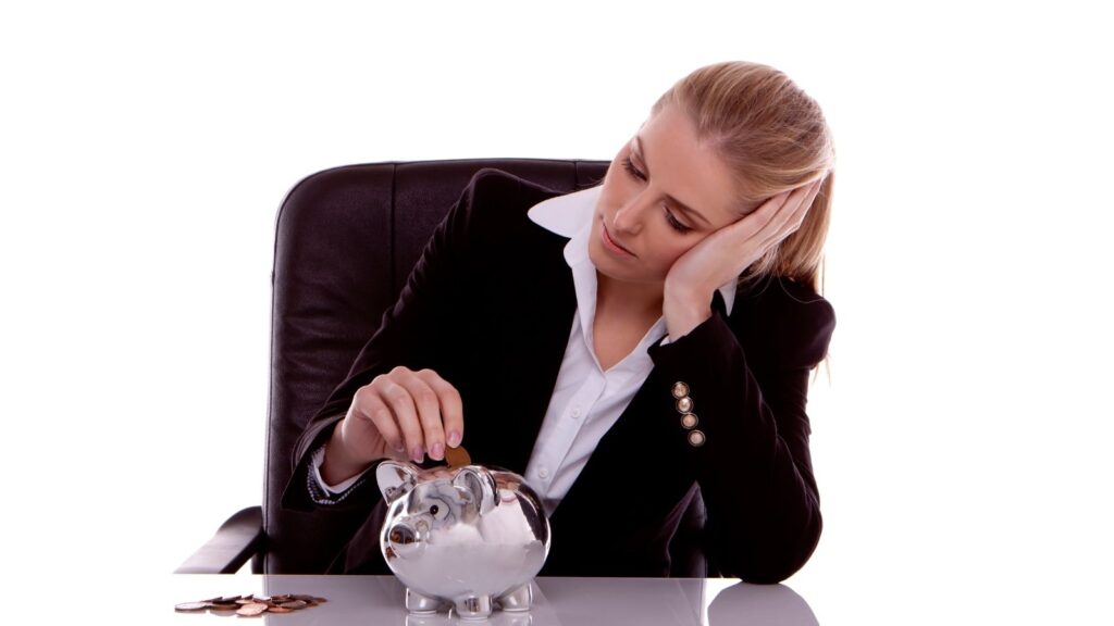 Young woman putting money in a piggy bank thinking about thriving in a recession