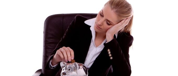 Young woman putting money in a piggy bank thinking about thriving in a recession