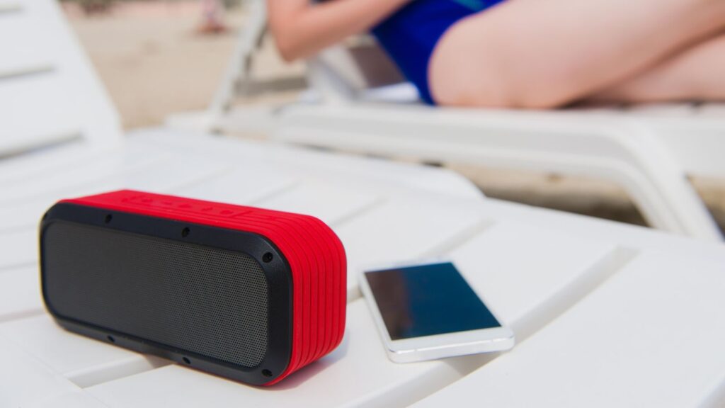 Photo of bluetooth speaker next to woman at beach