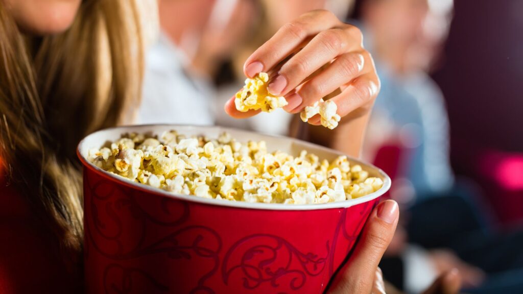 Woman eating popcorn at movie theater